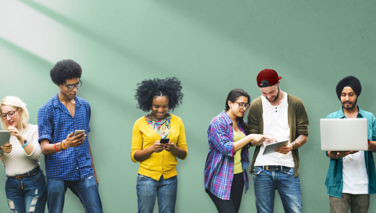 Un groupe diversifié d'hommes et de femmes sourient et utilisent la technologie sans fil pour collaborer en équipe.